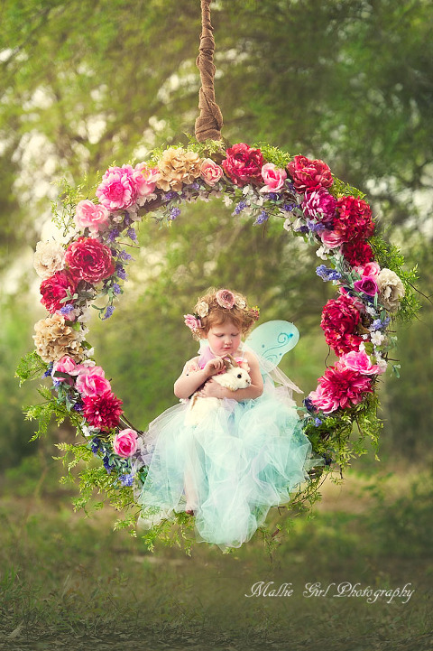 Little red headed two year old on a flower seing with a bunny rabbit